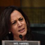 Woman speaking into a microphone while frowning.