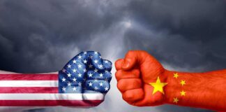 Two fists with US and China flags facing