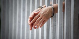 Hands in handcuffs through jail bars