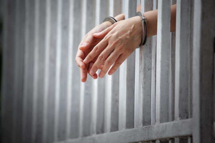 1018630735 featured image Hands in handcuffs through jail bars