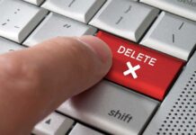 Finger pressing red delete key on keyboard