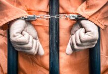 Hands cuffed in front of prison bars
