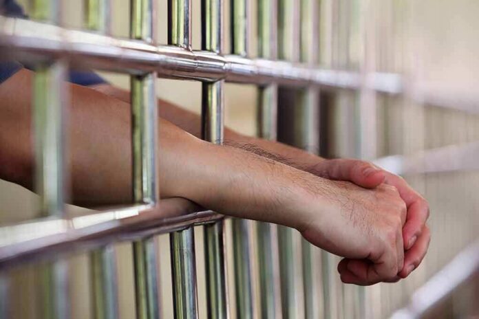 314390225 featured image Hands clasped behind metal prison bars