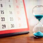 Calendar and hourglass with blue sand