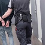 Officer escorting handcuffed person down hallway