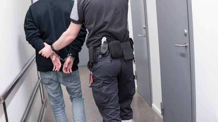1082126789 featured image Officer escorting handcuffed person down hallway