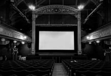 Empty theater with ornate decor and projection screen.