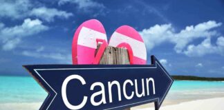 Cancun sign on a beach with flip-flops.