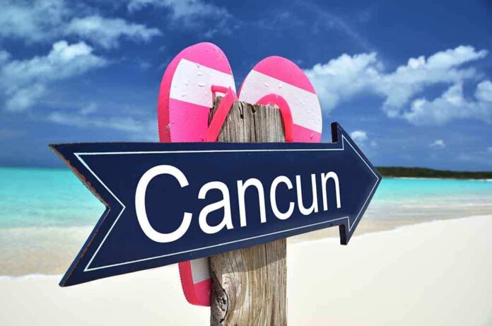 Cancun sign on a beach with flip-flops.