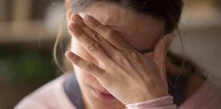 Woman covering face with hand looking stressed