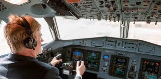 Pilot in cockpit operating airplane controls.