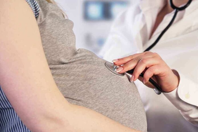 261991445 featured image Doctor uses stethoscope on pregnant woman's belly.