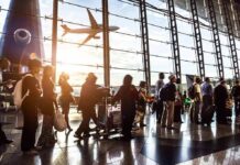 Crowd of travelers in airport terminal with airplane outside
