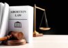 Gavel and abortion law book next to scales