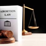 Gavel and abortion law book next to scales