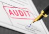 Audit stamp and pen signing a document