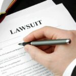 Hand holding pen filling out lawsuit form