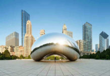 Cloud Gate sculpture with skyline of skyscrapers behind it