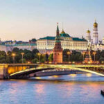 Illuminated bridge and Kremlin complex across river at twilight