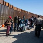 Group of people at border wall with patrol agents