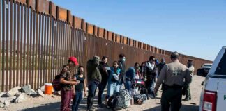 Group of people at border wall with patrol agents