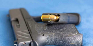 Handgun on blue fabric with visible bullet cartridge
