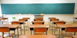Classroom with wooden desks and empty green chalkboard