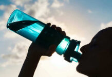Silhouette of person drinking from a water bottle