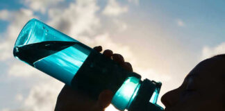 Silhouette of person drinking from a water bottle