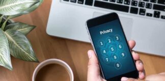 Typing privacy passcode on smartphone near laptop and coffee
