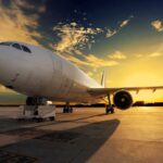 An airplane parked on the runway during sunset with a colorful sky