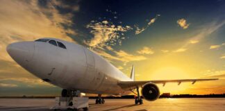 An airplane parked on the runway during sunset with a colorful sky