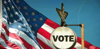 A vintage 'Vote' sign in front of an American flag
