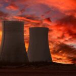 Silhouette of cooling towers against a vibrant sunset sky
