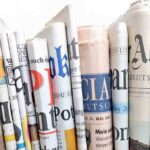 A collection of rolled newspapers displaying various headlines and designs