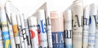 A collection of rolled newspapers displaying various headlines and designs