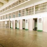 Interior view of a prison cell block with empty cells and security bars