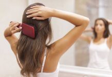 A woman brushing her long hair in front of a bathroom mirror