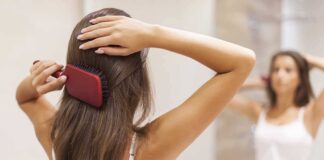 A woman brushing her long hair in front of a bathroom mirror