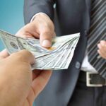 Two hands exchanging cash in a business setting