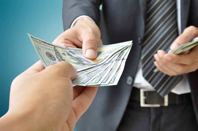 Two hands exchanging cash in a business setting