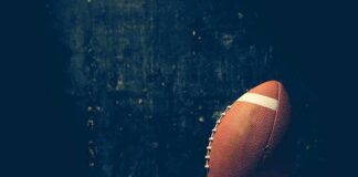 An American football resting on a wooden surface against a dark background