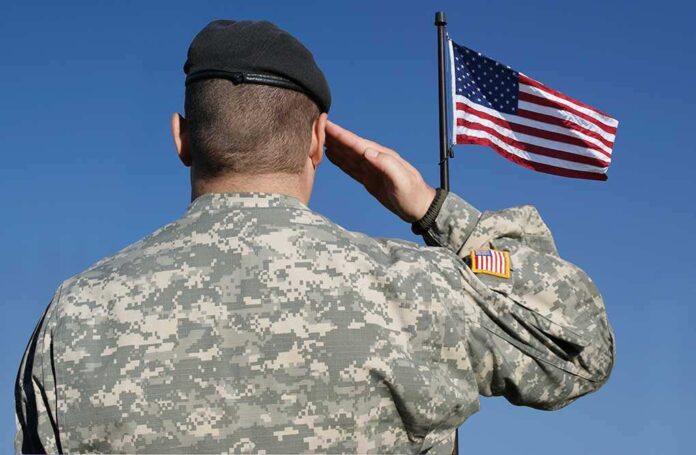 Soldier in military uniform saluting in front of an American flag