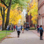 People walking on a college campus in autumn.