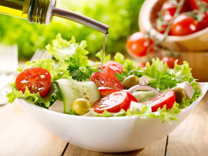Fresh salad being drizzled with olive oil