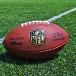 An NFL football resting on a green grass field