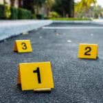 Crime scene markers on asphalt with bullet casing.