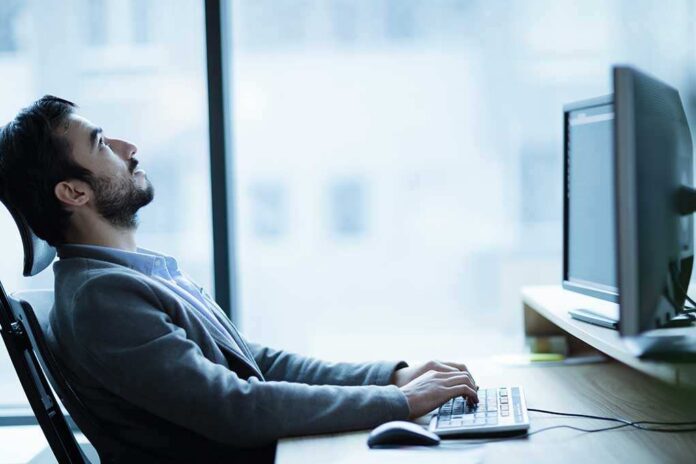 Man sitting at a desk, looking up while typing on a computer