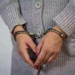 A person wearing handcuffs with their hands clasped together