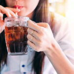 Person drinking soda from a glass mug
